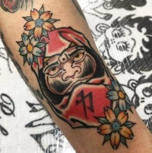Hình xăm chữ Kanji trong búp bê Daruma tượng trưng cho sự kiên trì, quyết tâm và khả năng vượt qua nghịch cảnh để đạt được mục tiêu